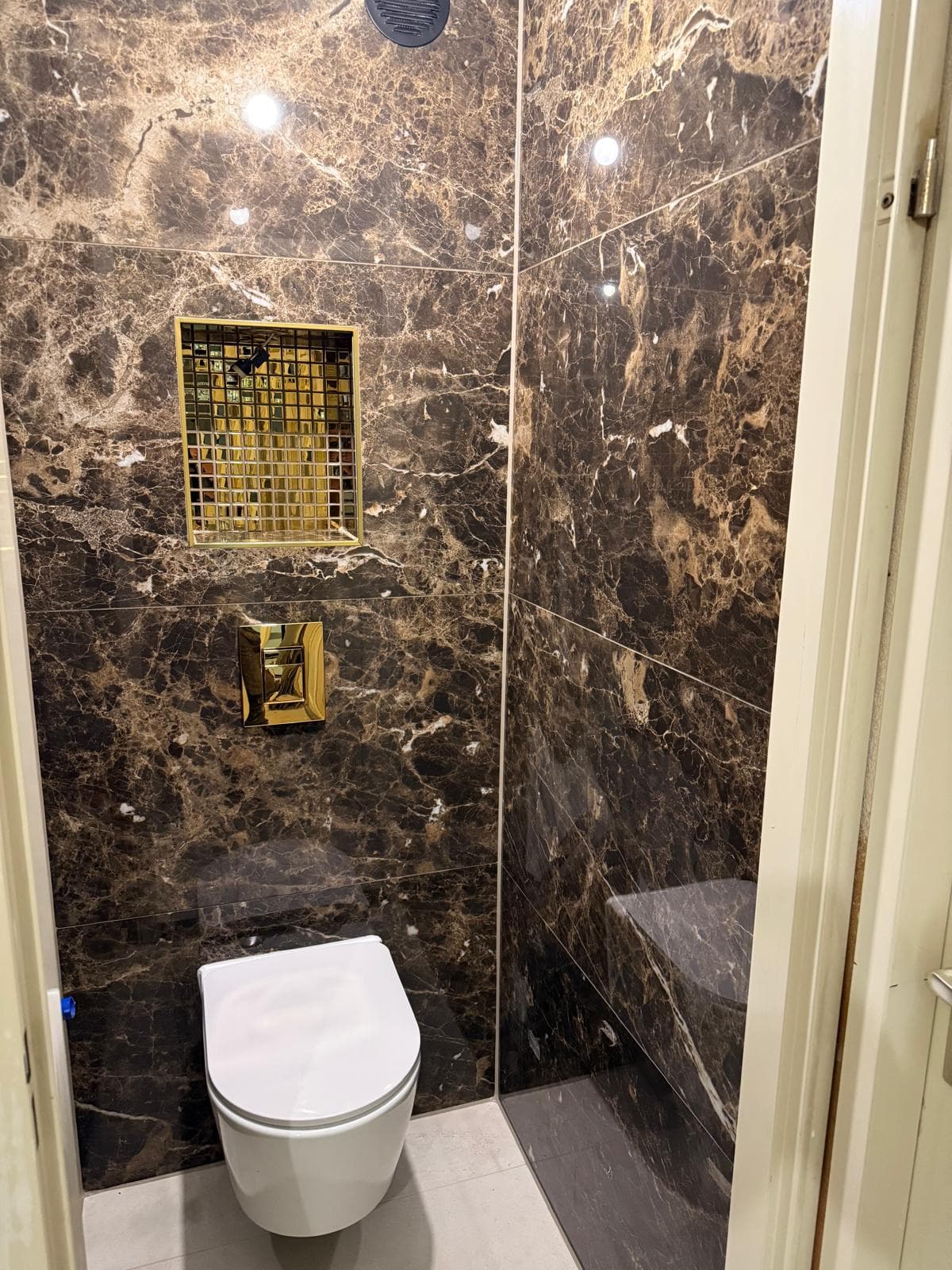 Toilet met tegels in marmerlook, gouden nis en hangtoilet